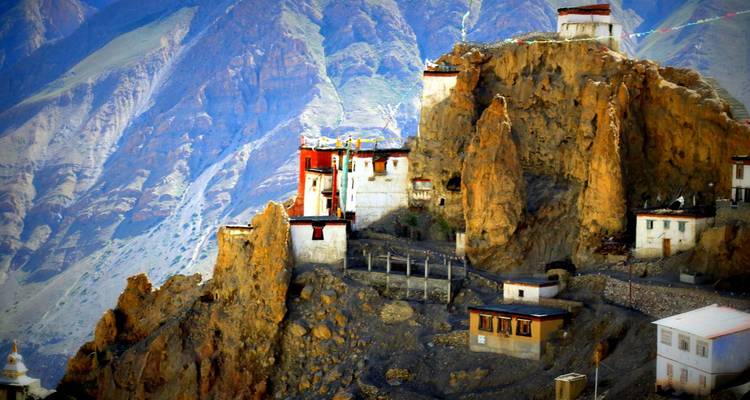 Dramatic cliff-side monastery perched on rugged golden rock formations.