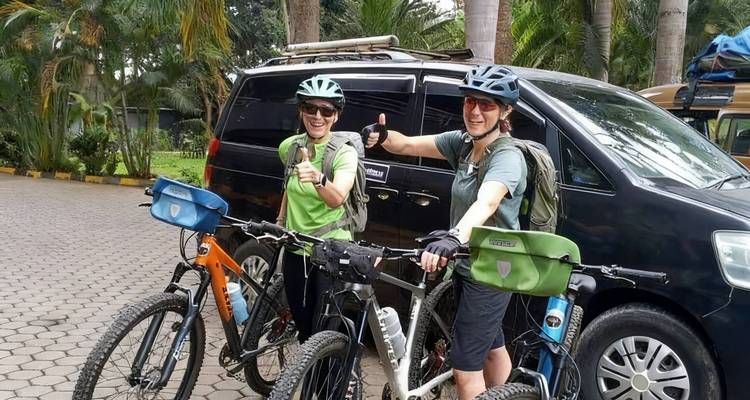 Two cyclists give thumbs-up beside their bikes and support van before starting a ride