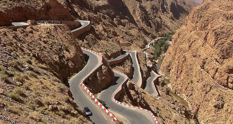 Spectacular serpentine road winds dramatically through steep red-rock canyon walls.