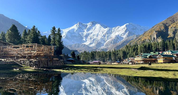 Le Nanga Parbat couvert de neige s'élevant majestueusement au-dessus des forêts de pins et des chalets de montagne se reflétant dans un étang tranquille aux Prairies des Fées.