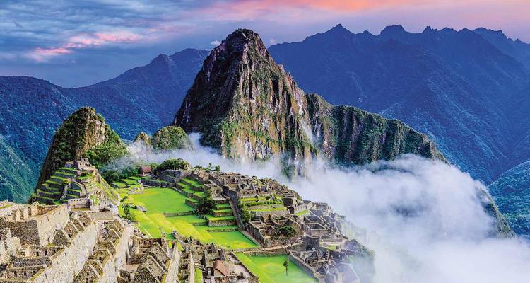 Vivid view of Machu Picchu ruins nestled below steep green peak with drifting morning cloud