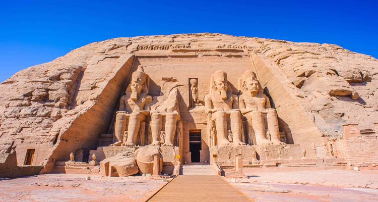 Majestic facade of Abu Simbel temple with colossal statues under a deep blue sky.