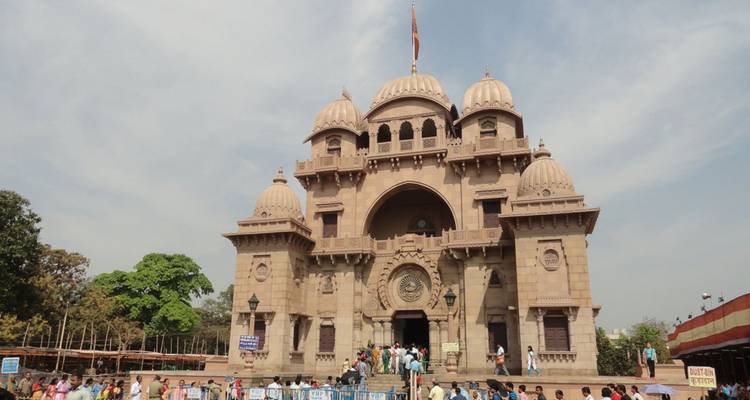 Belur Math temple complex with devotees entering under a pale blue sky.