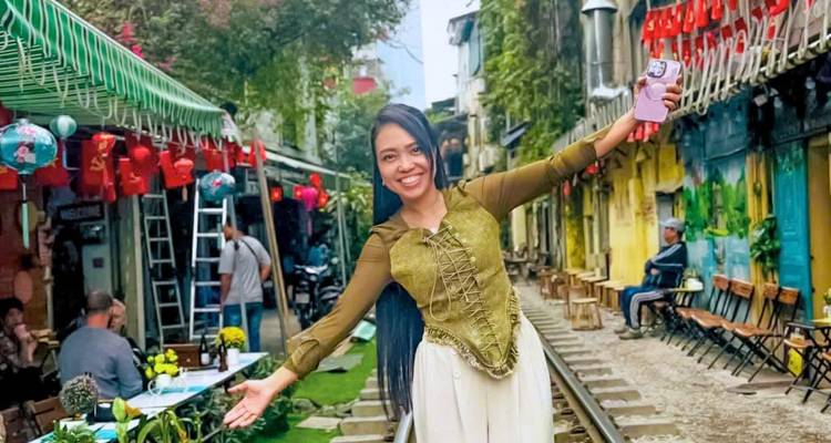 Woman posing on Hanoi's famous Train Street lined with cafes and lanterns.