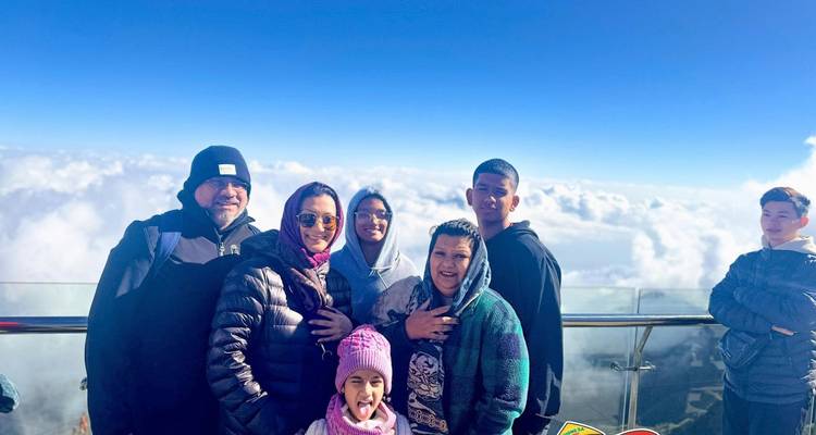 Family group at high mountain viewpoint above clouds with sticker overlay.