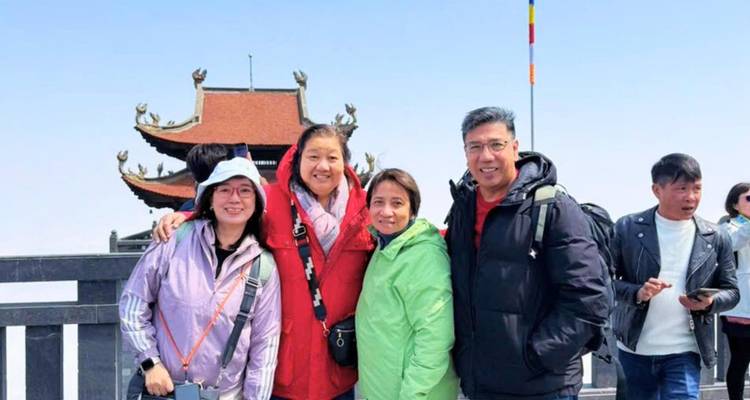 Small group of travelers wearing bright jackets at a mountain shrine terrace.