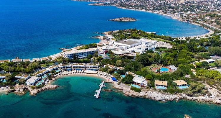 Vue aérienne d'un complexe de villégiature de luxe sur une péninsule courbe le long de la Riviera d'Athènes.