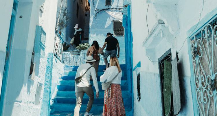 Small group of young travellers climbing bright blue steps between whitewashed houses.