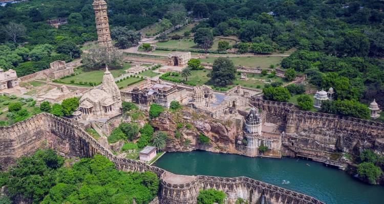Vue aérienne du vaste complexe du Fort de Chittorgarh avec lac, tours et paysage verdoyant environnant.
