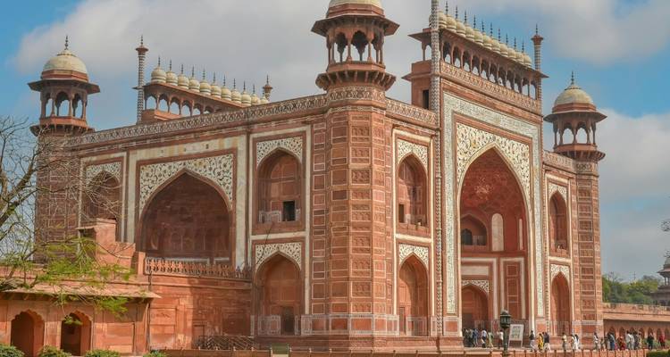 Großes rotes Sandstein-Tor zum Taj-Mahal-Komplex unter blauem Himmel.