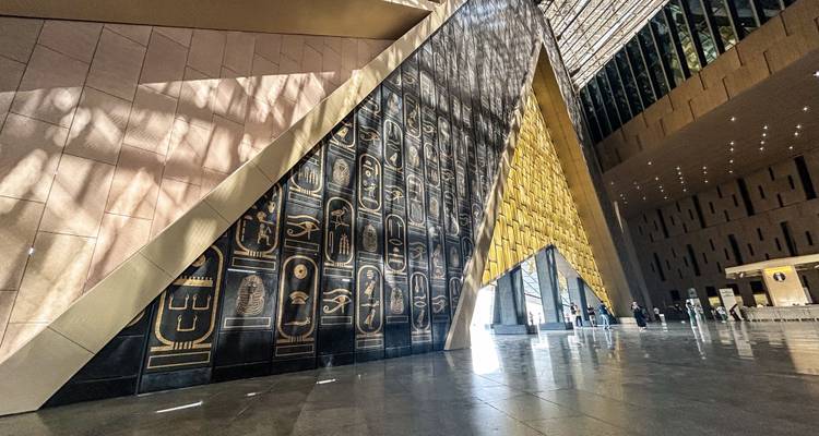 Modern interior of Egypt’s Grand Museum with tall engraved wall and dramatic lighting.