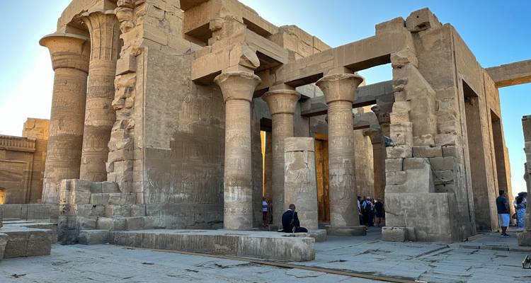 Ancient sandstone columns and walls of Kom Ombo Temple with visitors exploring the site.