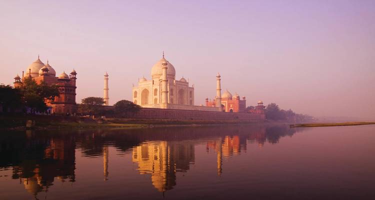 Taj Mahal glows in soft dawn light reflected across the Yamuna River.