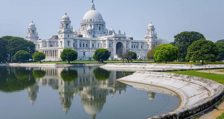 Majestic white marble Victoria Memorial reflected perfectly in still water on a clear morning.