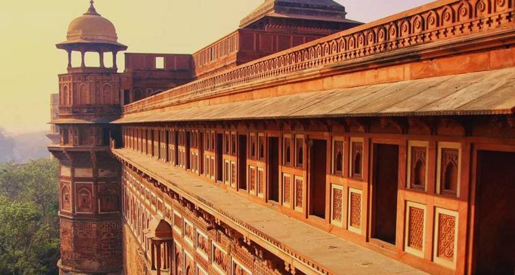 Warm sunrise light bathes the red-sandstone walls and watchtower of Agra Fort