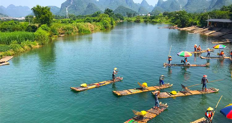 Des radeaux en bambou avec des touristes flottant sur une rivière cristalline au milieu de pics karstiques