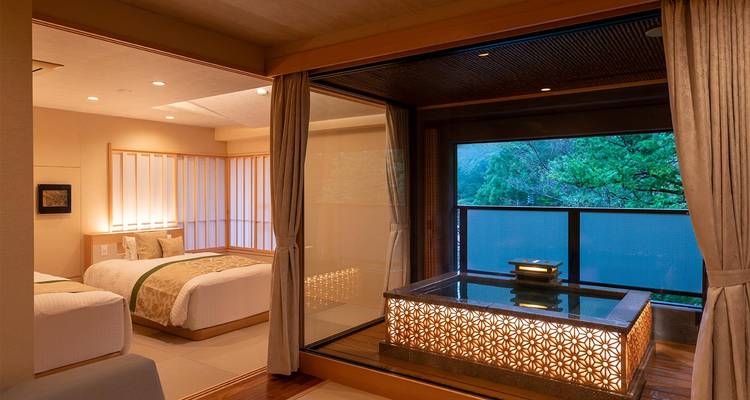 Suite de ryokan élégante dotée de lits jumeaux et d'un onsen privé en plein air avec vue sur la forêt