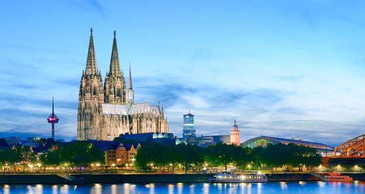 Evening skyline of Cologne with illuminated cathedral and Rhine river reflections