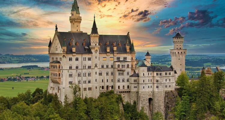 Fairy-tale Neuschwanstein Castle perched on a forested cliff at sunset