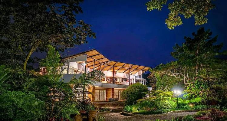 Élégant lodge en forêt tropicale illuminé la nuit parmi de luxuriants jardins tropicaux