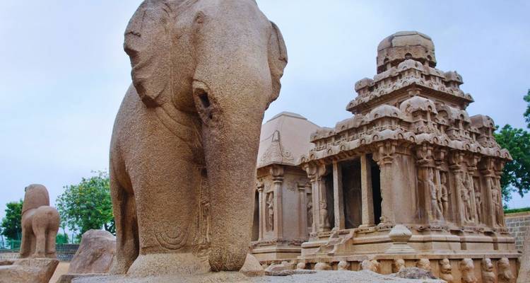 Stone elephant sculpture beside intricately carved ancient temple at Mahabalipuram