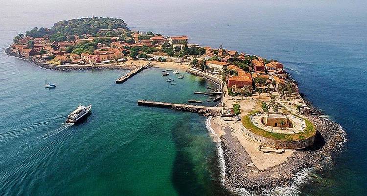 Aerial view of Île de Gorée with its forts, ochre buildings and surrounding turquoise Atlantic waters.