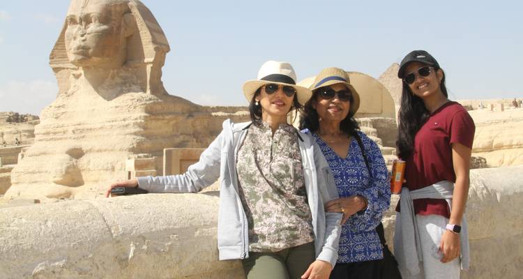 Trois femmes posent heureusement à côté du Sphinx sous un ciel dégagé.