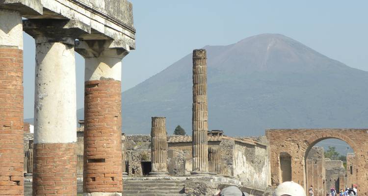 Ancient columns and ruins of Pompeii with Mount Vesuvius looming in the background.