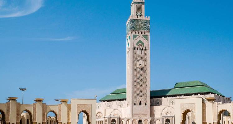 Minarete de la Mezquita Hassan II y arcos circundantes bajo el cielo azul claro de Casablanca