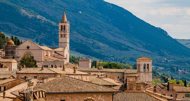 Stone bell tower and rooftops of Assisi set against Umbrian hills