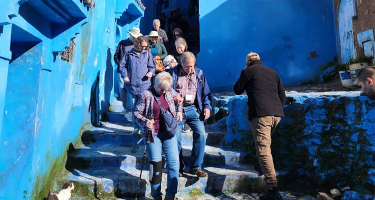 Tour group descending the blue-washed steps of Chefchaouen’s medina.