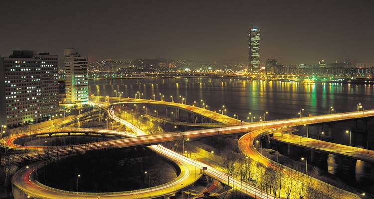 Nachtpanorama van Seuls Han-rivier met gloeiende snelwegbruggen en het 63-gebouw dat weerspiegeld wordt in het rustige water