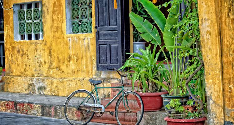 Geel geschilderd erfgoedgebouw met vintage fiets en plantenpotten in het oude stadje Hoi An