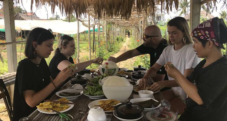 Reizigers delen een boerderij-naar-tafel maaltijd onder een rieten pergola in het dorp Tra Que