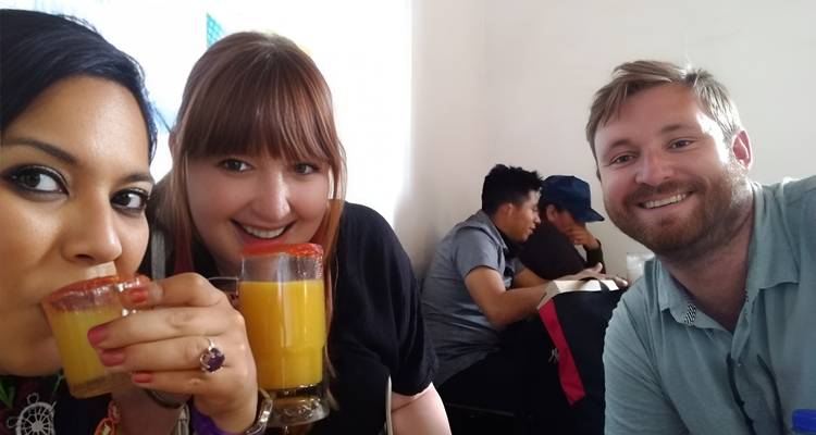 Selfie von drei fröhlichen Reisenden mit orangeumrandeten Cocktails in einem zwanglosen Restaurant