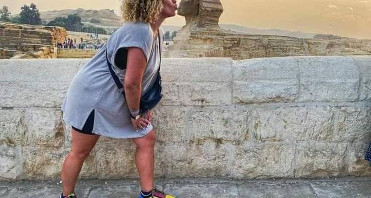 Un turista se inclina hacia adelante como si estuviera besando la Esfinge al atardecer, usando la técnica de fotografía de perspectiva.