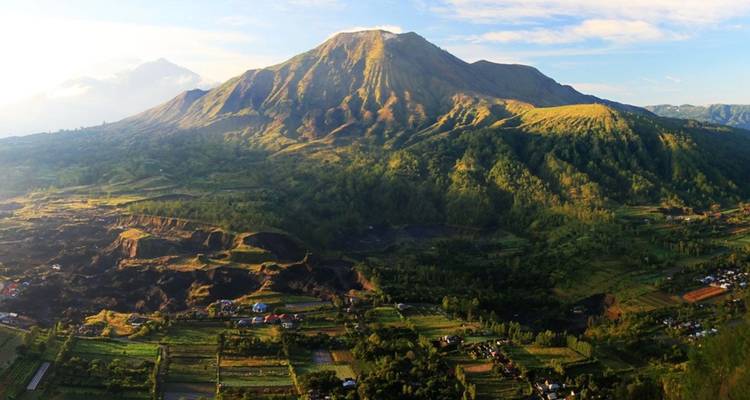 Panoramic view of a conical volcano towering over patchwork farmland and valleys.