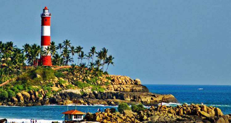 Der rot-weiße Vizhinjam-Leuchtturm steht auf einem felsigen Vorgebirge mit Palmenbestand neben dem Arabischen Meer in Kovalam.