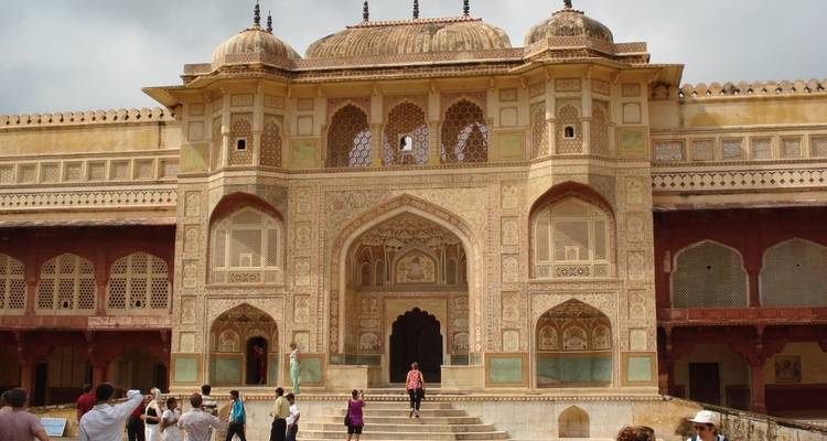 Verziertes Tor der Amber Fort mit Touristen, die die reich bemalte Fassade erkunden.