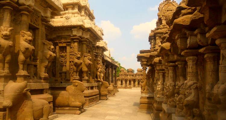Narrow temple corridor adorned with weathered stone lion pillars and ornate carvings.