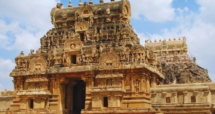 Massive Brihadeeswarar Temple with richly carved sandstone façade under a blue sky.