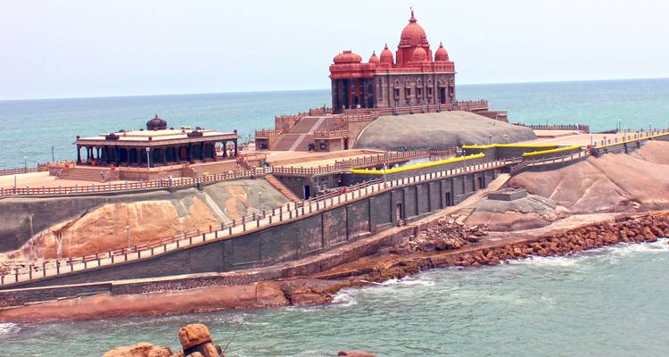 Vivekananda Rock Memorial op een rotsachtig eilandje in turkooizen zee onder een mistige hemel.