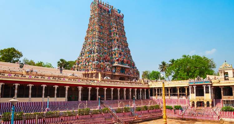 Uitgebreide binnenplaats van de Meenakshi Temple met een indrukwekkende, veelkleurige gopuram en gestreepte muurpatronen.