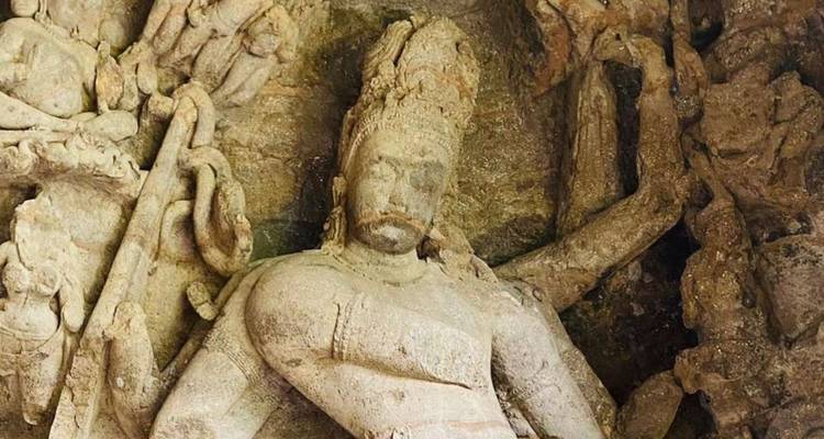 Close-up of an intricately carved stone Hindu deity inside an ancient cave temple.