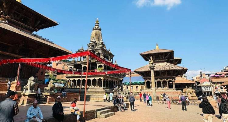 Bhaktapur Durbar Square bustles with locals and tourists amid pagoda temples under clear blue skies.