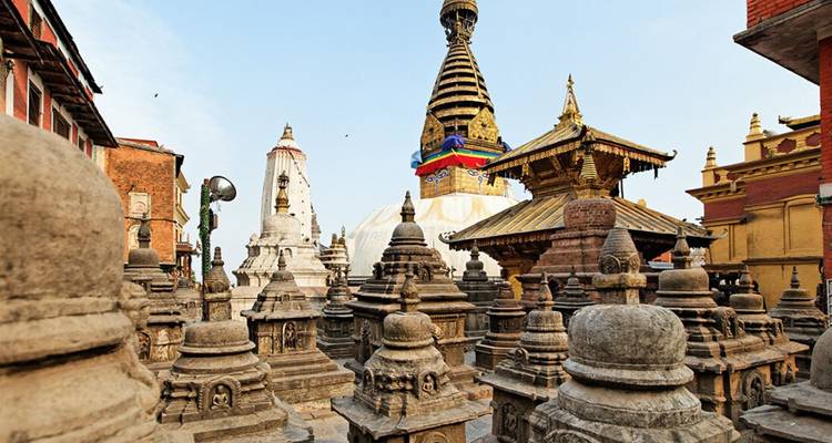 Stone stupas surround a colorful Swayambhunath spire in Kathmandu’s sacred complex.