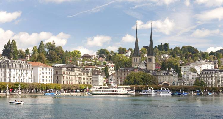 Le front de lac ensoleillé de Lucerne offre des hôtels élégants, les deux clochers d'église caractéristiques et des bateaux sur le lac scintillant.