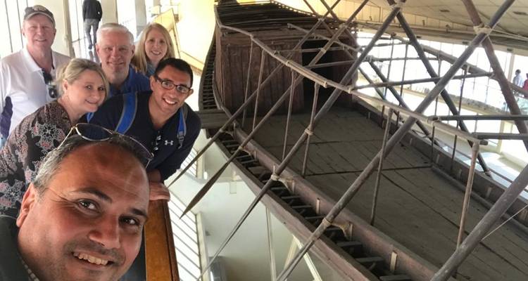 Bezoekers selfie in het oude Khufu zonneboten museum naast houten scheepswrakken.