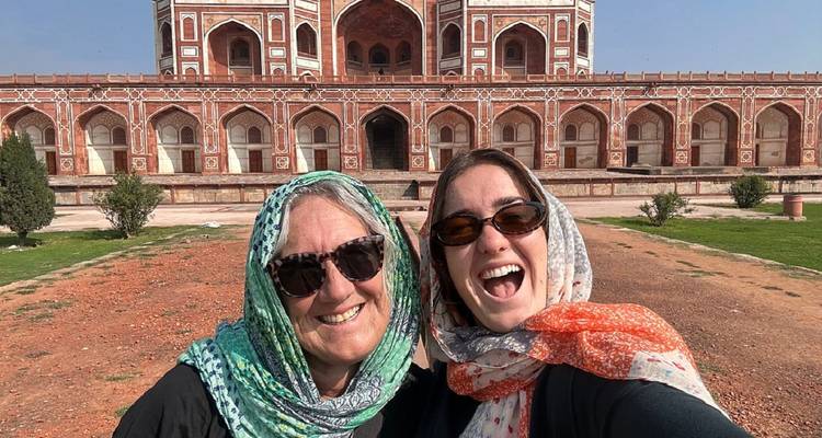 Deux femmes portant des foulards colorés sourient largement pour un selfie devant les élégantes arcades en grès rouge du Tombeau d'Humayun.