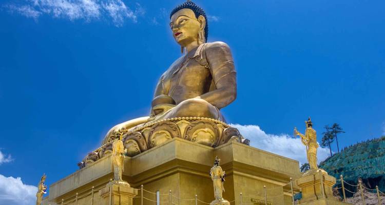 The giant golden Buddha Dordenma statue sits majestically against a vivid blue sky on a hilltop.